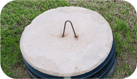 A concrete lid with an iron handle on top.